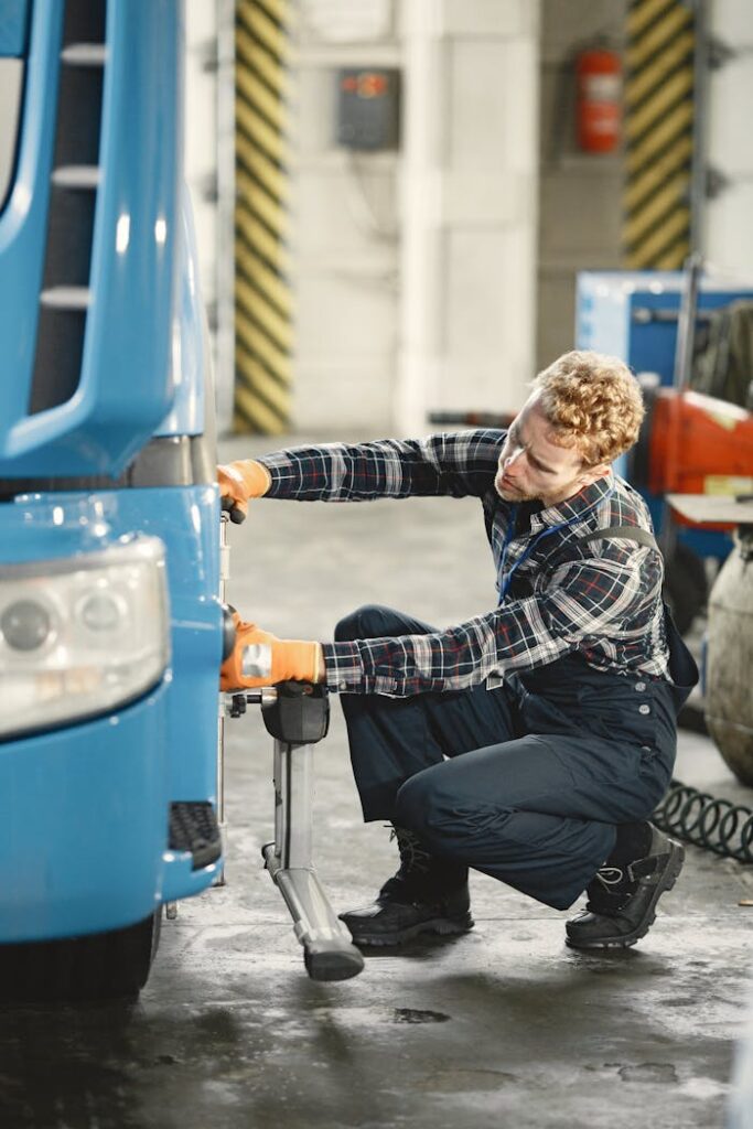 Mechanic working on a truck inside a workshop with tools and equipment.